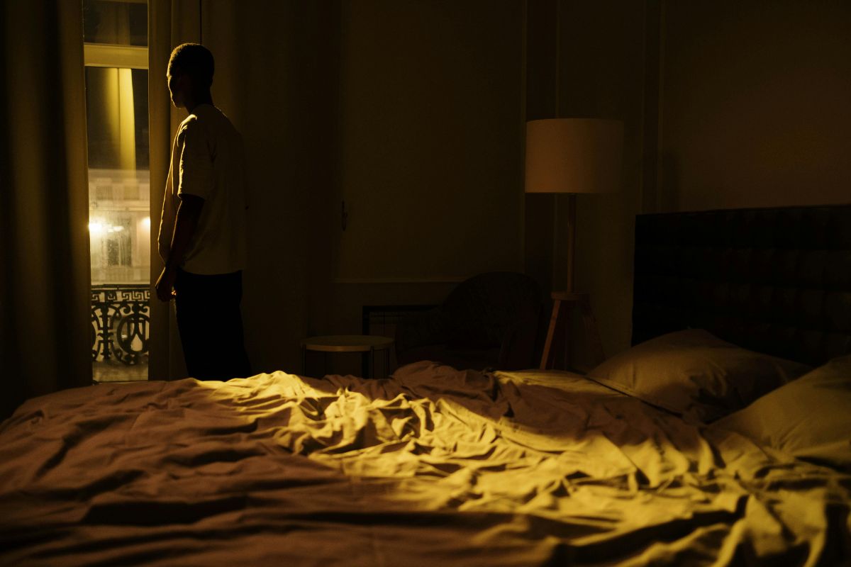 Man in dark room, standing and staring out of the window at night